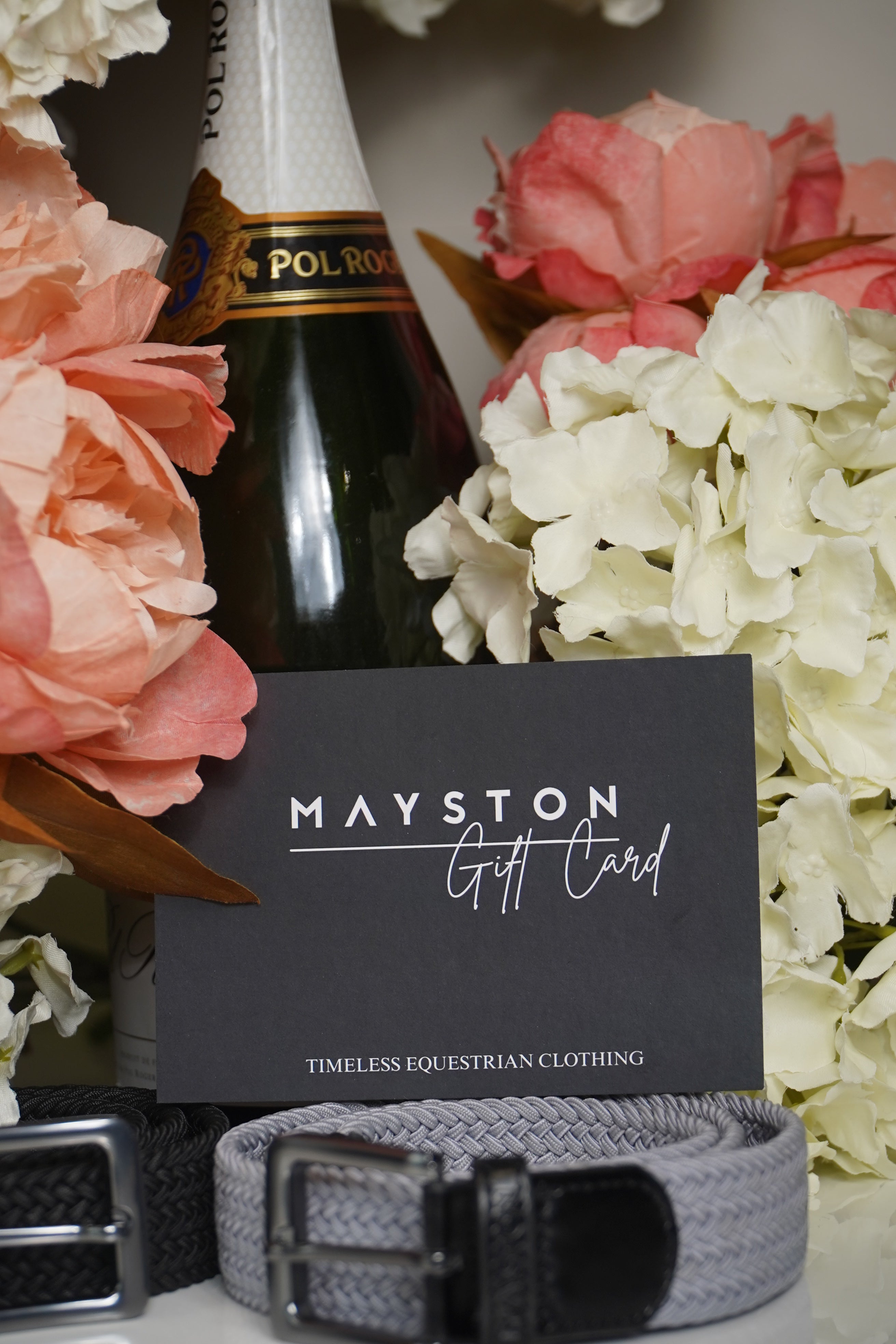 Mayston belt with a bottle of Pol Roger champagne and flowers on a white background