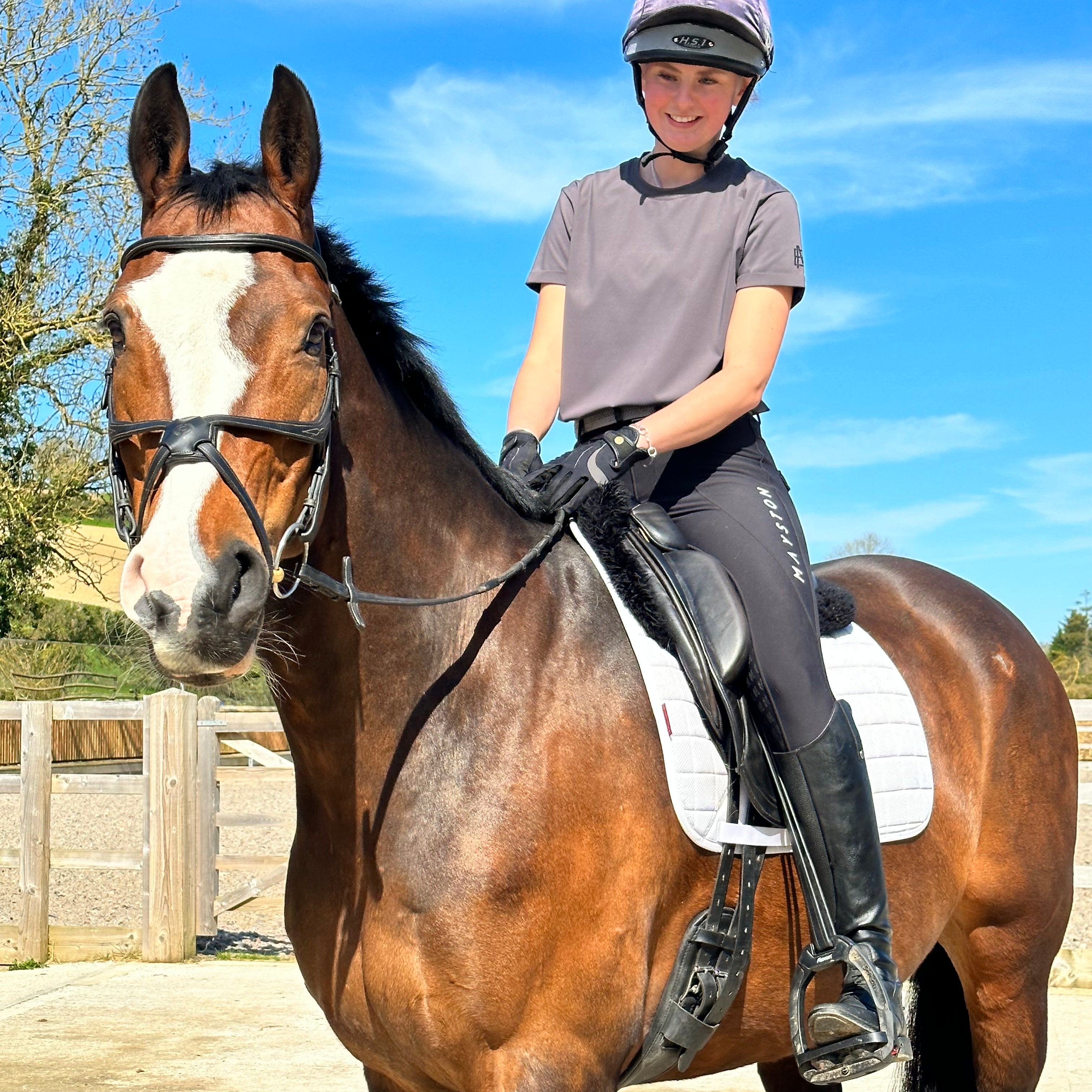 A person riding a horse while wearing a grey Durlston Tee. luxury quality t shirt and fabric is specially crafted for active duty, providing flexibility and ease of movement for any busy lifestyle. An ideal choice for a day at the yard, in the saddle, or during your grooming duties, its loose-fitting design guarantees complete freedom.