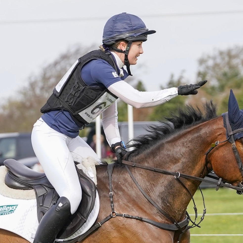Sleek silhouette baselayer top subtle Mayston branding, maximum coverage without compromising style, next-level performance with a bold, minimalist look. Moisture-wicking, breathable fabric with four-way stretch, it keeps you cool and comfortable. Training, Everyday or competition wear. Short Sleeve 1/4 zip with collar. Navy with White Branding. Woman riding cross country on a horse