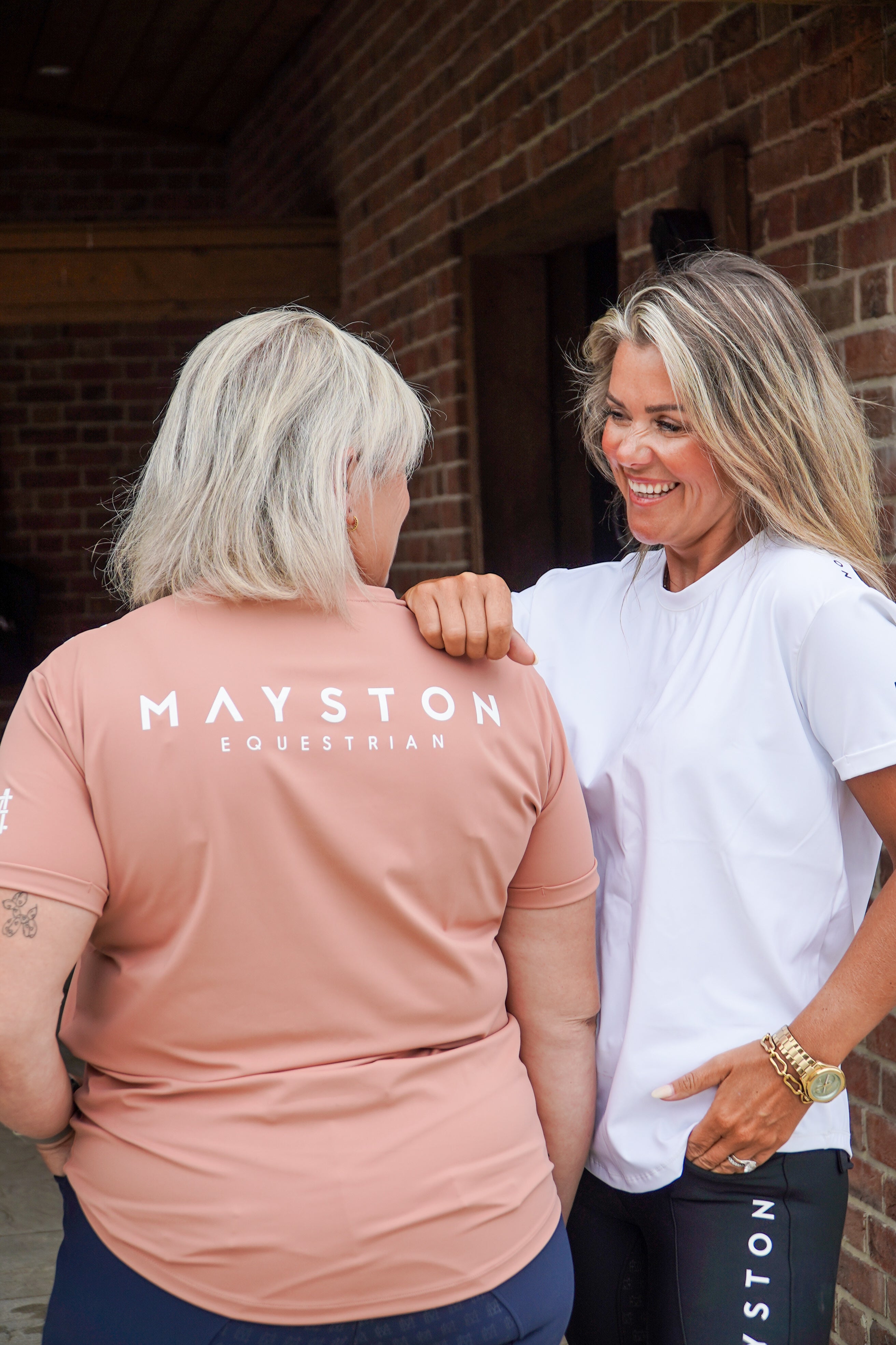 Two women standing close together, one wearing a pink 'Mayston Equestrian' shirt, against a brick wall.
luxury quality t shirt and fabric is specially crafted for active duty, providing flexibility and ease of movement for any busy lifestyle. An ideal choice for a day at the yard, in the saddle, or during your grooming duties, its loose-fitting design guarantees complete freedom.