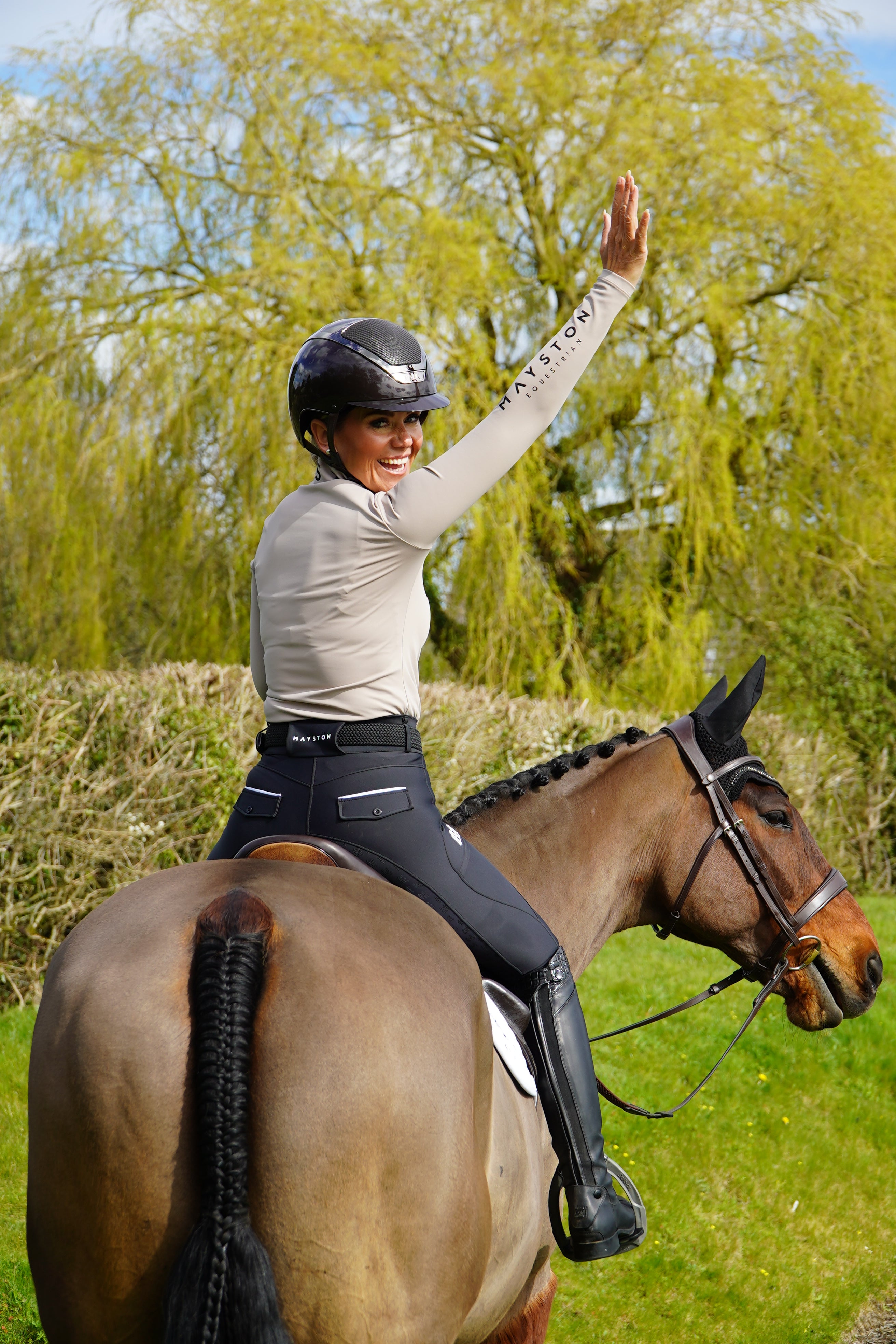 Person interacting with a horse in a natural setting. classic equestrian fit with belt loops and secure fastening, combining traditional style with modern performance. Finished in sleek Classic Black with subtle white detailing and high-gloss silicone logos, they’re the perfect balance of elegance and functionality.