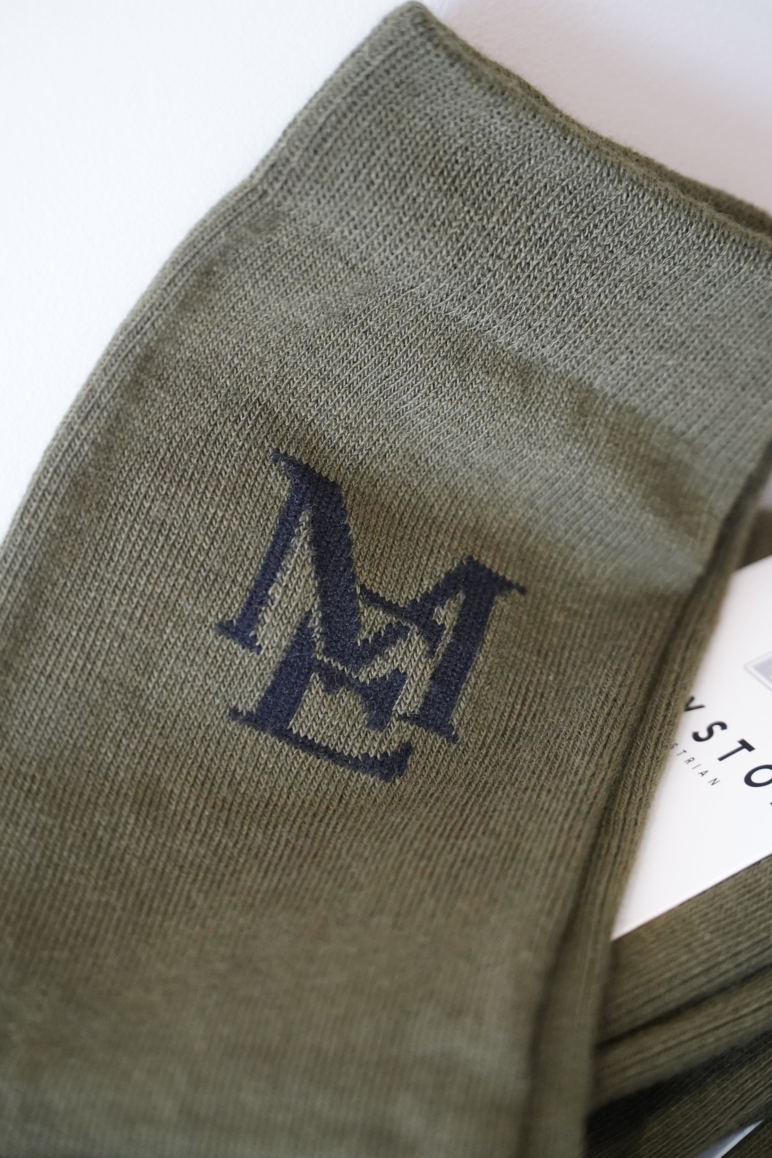 Green sock with a black logo on a white background. 