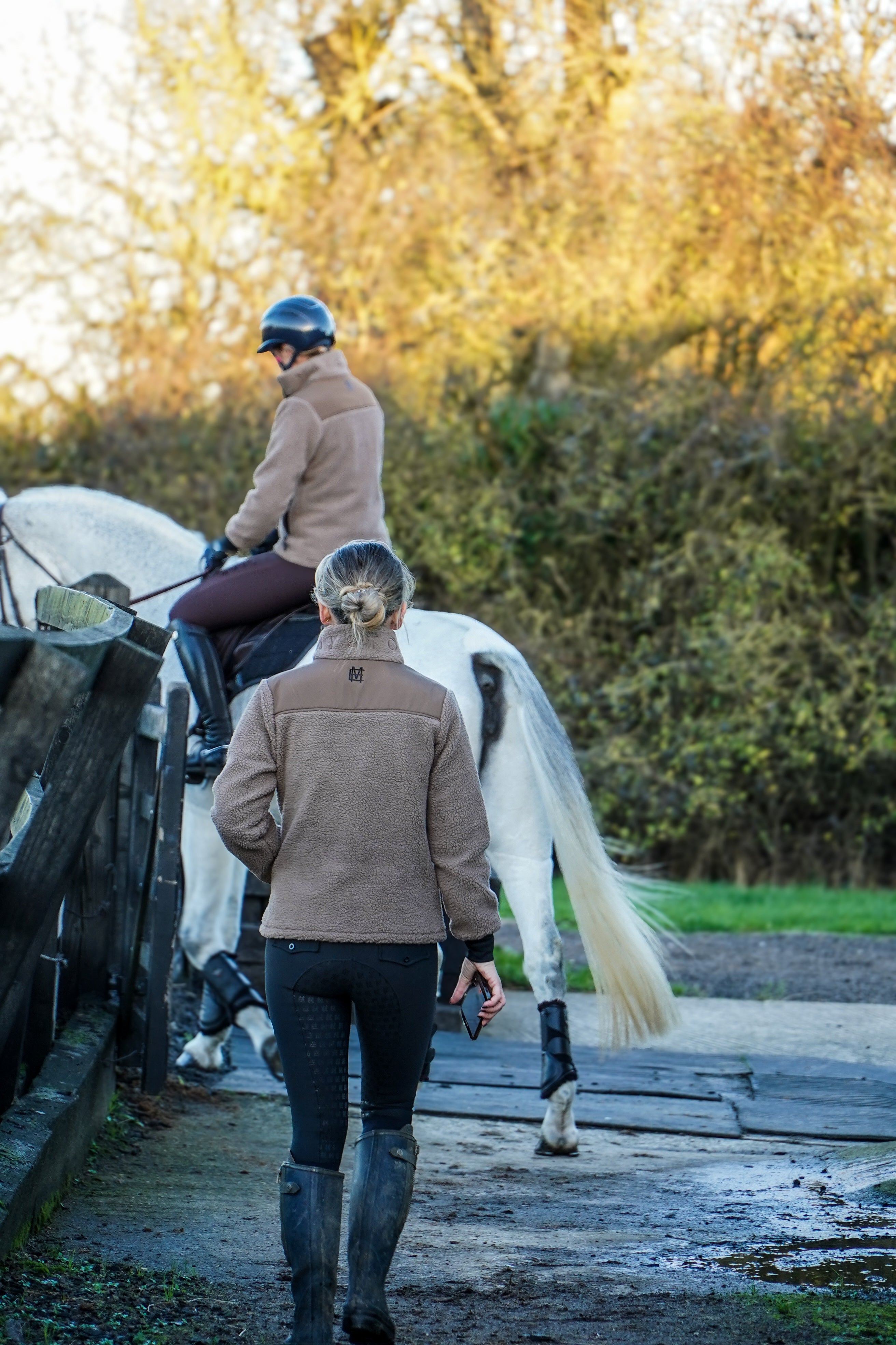 Two people with a horse walking on a path in a natural setting. brown fleece jacket